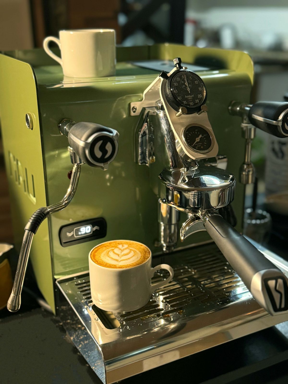 Máquina de espresso verde da Numa com uma xícara de latte art recém-preparada