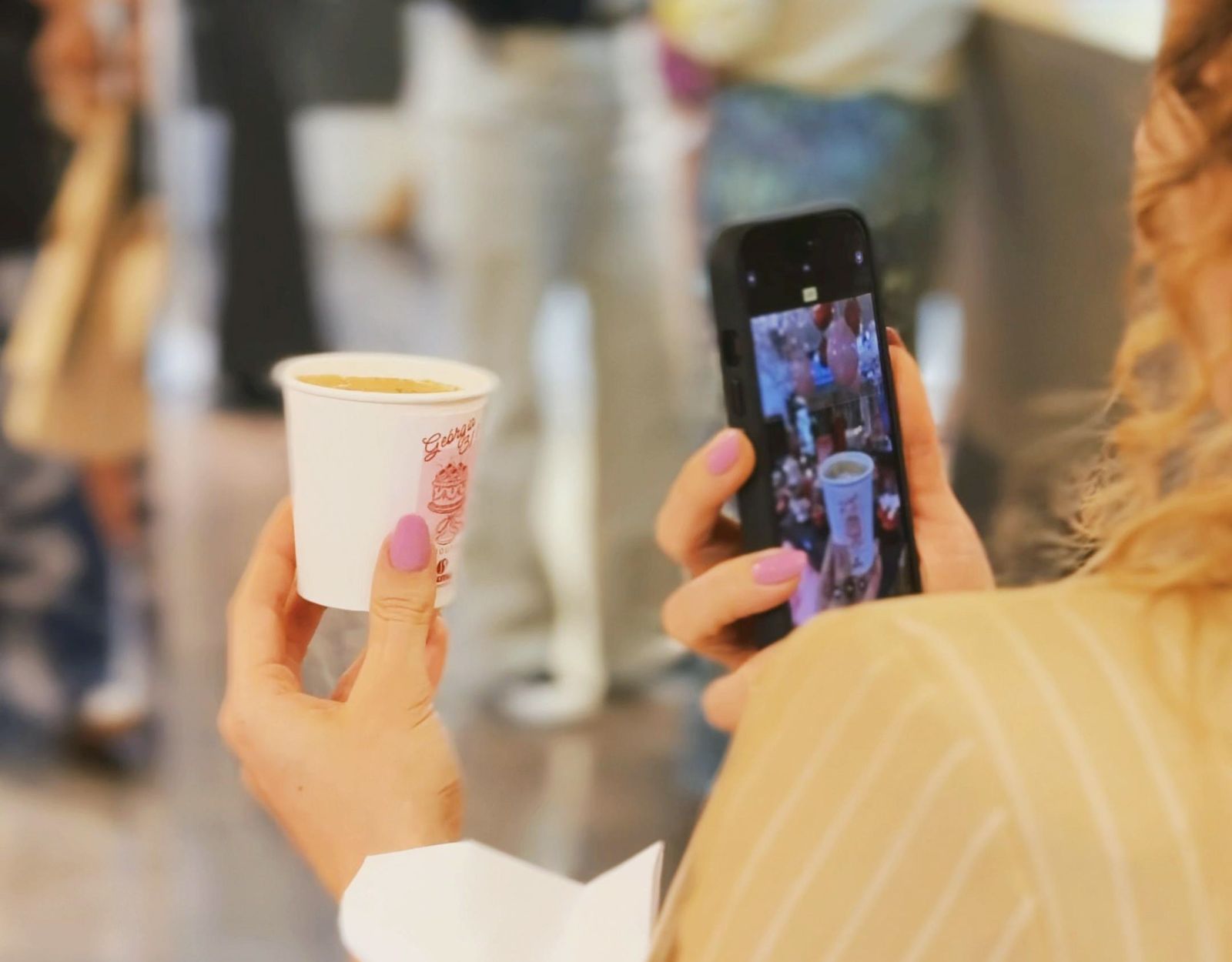Convidada fotografando um copo de café personalizado da Numa