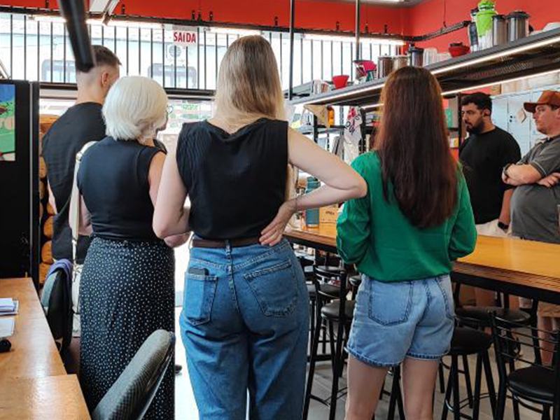 Balcão movimentado de uma cafeteria, com clientes e baristas